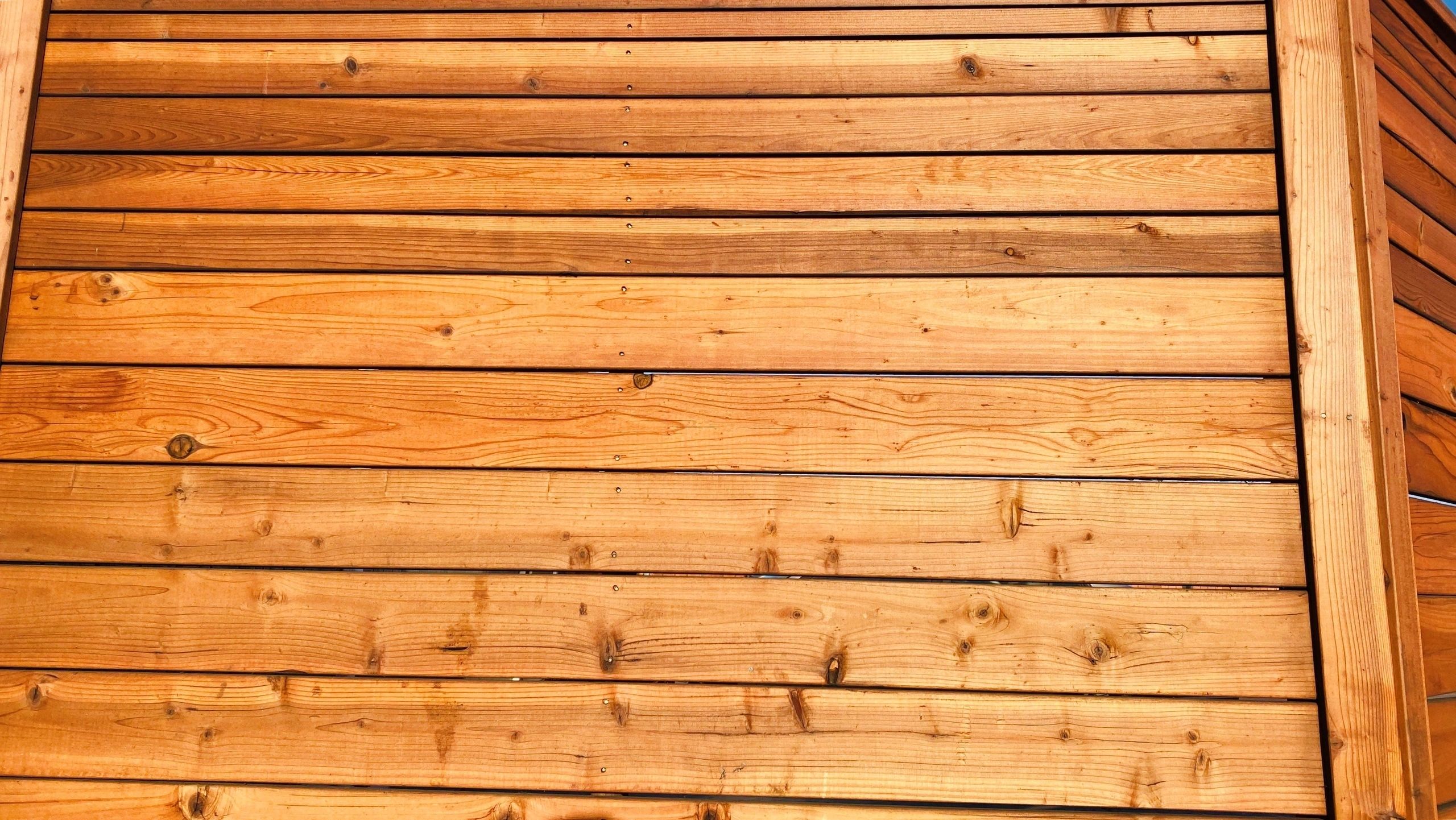 Close-up of freshly stained redwood fence boards showing wood grain